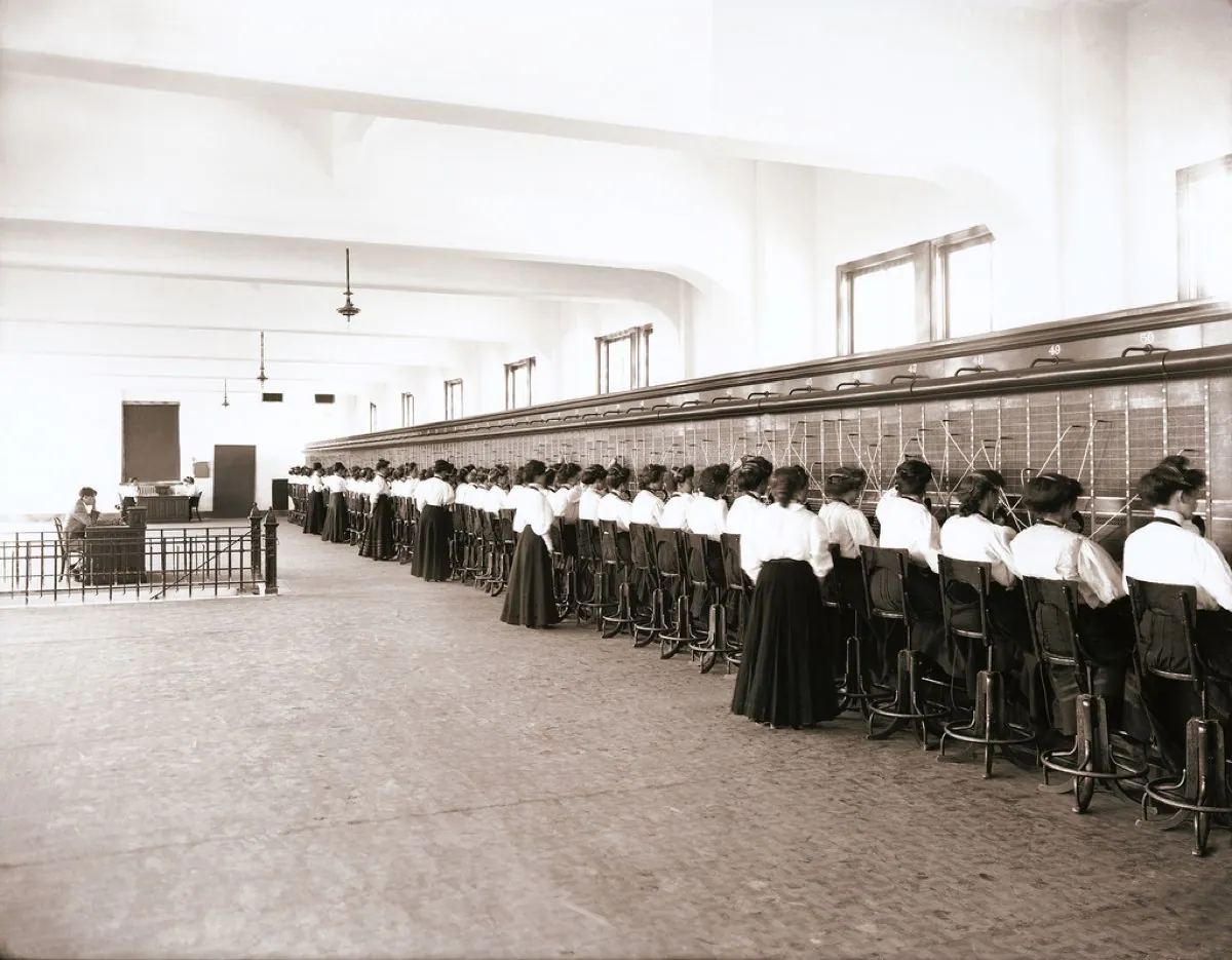 Rows of telephone operators seated at a manual switchboard in 1907, connecting calls by hand.